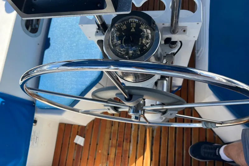 Slide: The Image of Steering wheel and compass of 1988 Catalina 34 mkI sailboat, with wooden deck and blue seating. - 10
