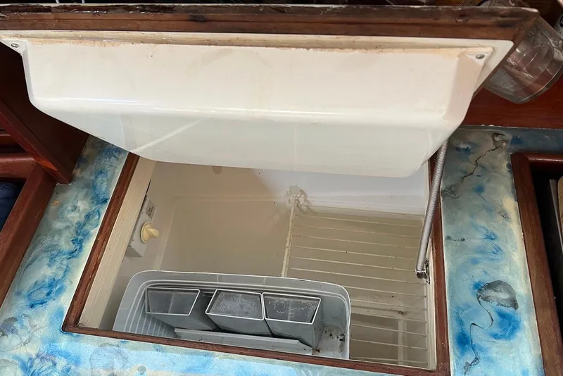 Slide: The Image of Open refrigerator compartment in 1988 Catalina 34 mkI sailboat, featuring a white interior and storage bins. - 32