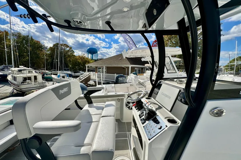 Slide: The Image of 2025 Parker 2600 Center Console boat interior with modern controls and seating at a marina. - 18