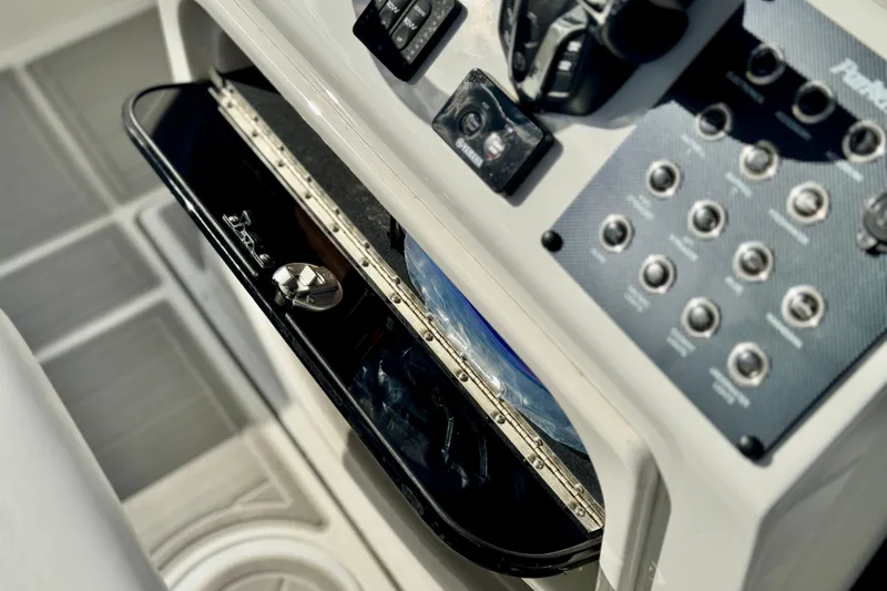 Slide: The Image of Control panel of 2025 Parker 2600 Center Console boat, featuring switches and storage compartment. - 21