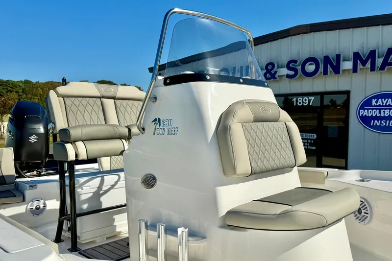 Slide: The Image of 2026 Key West 230 Bay Reef boat with cushioned seating and console, displayed outdoors. - 27