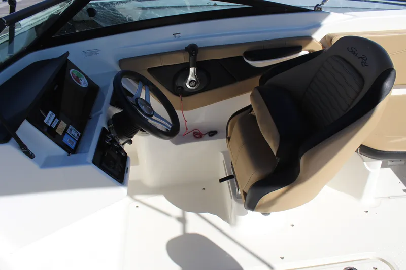 Slide: The Image of 2023 Sea Ray SPX 210 boat cockpit with steering wheel and beige seating. - 26