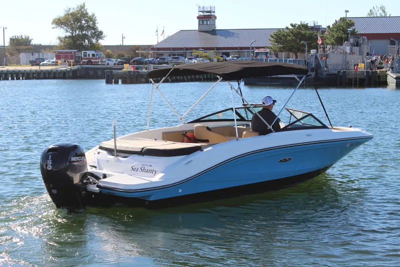 Slide: The Image of 2023 Sea Ray SPX 210 boat cruising on a sunny day near a marina. - 6