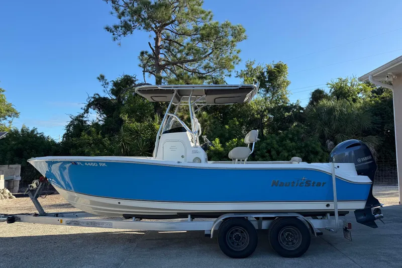 Slide: The Image of 2017 NauticStar 2302 Legacy boat on trailer, blue hull, Yamaha outboard, parked outdoors. - 0