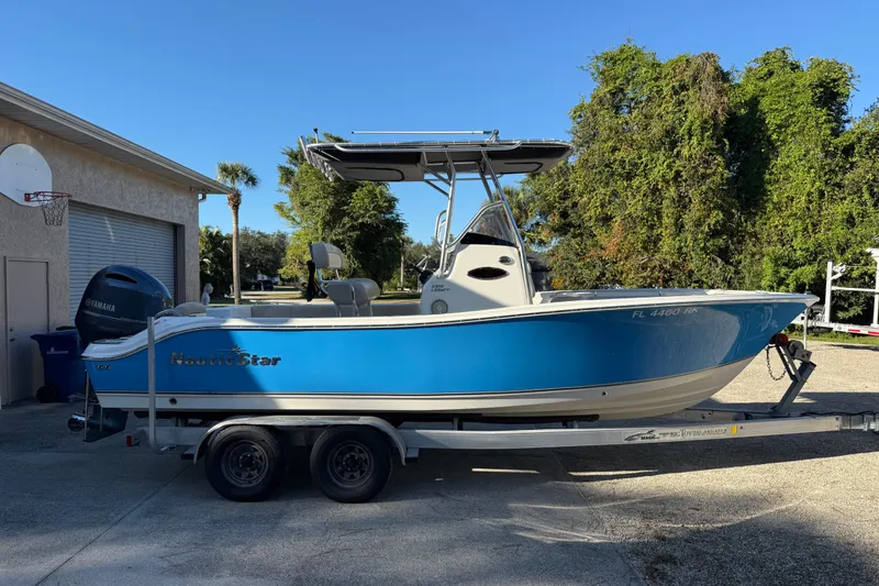 Slide: The Image of 2017 NauticStar 2302 Legacy boat on trailer, parked outdoors. - 1