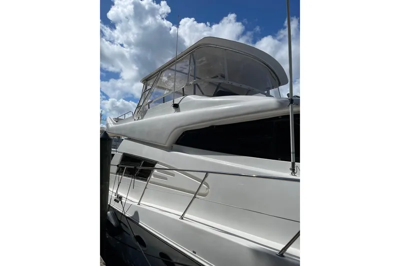 Slide: The Image of 1995 JOHNSON 65 Flybridge Motoryacht with sleek design against a cloudy sky backdrop. - 3