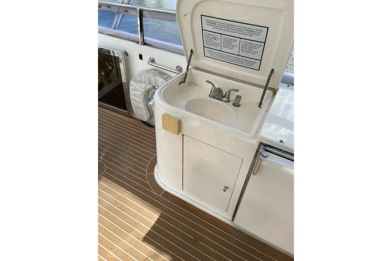 Slide: The Image of White cushioned seating on 1995 JOHNSON 65 Flybridge Motoryacht, with wooden deck flooring. - 32