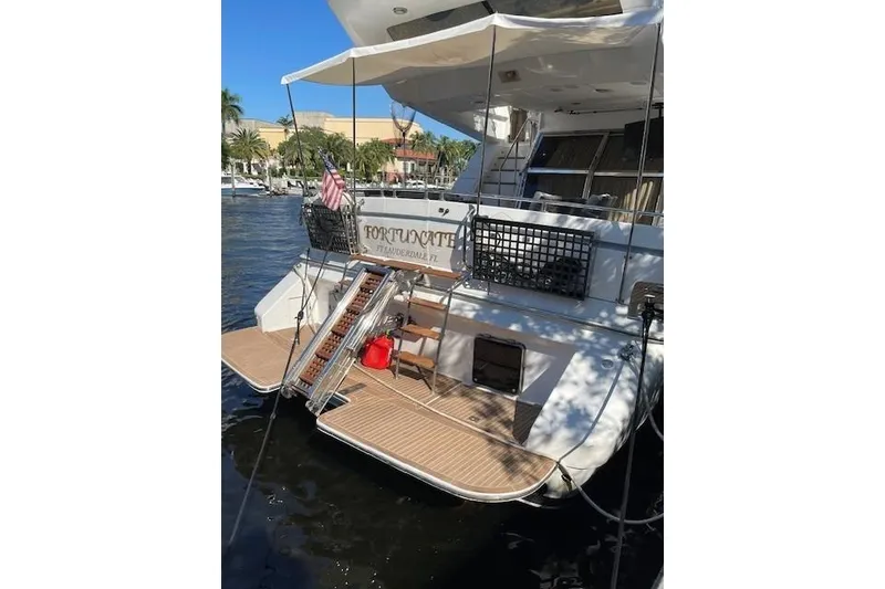Slide: The Image of 1995 Johnson Flybridge Motoryacht docked, featuring a spacious deck and American flag. - 6
