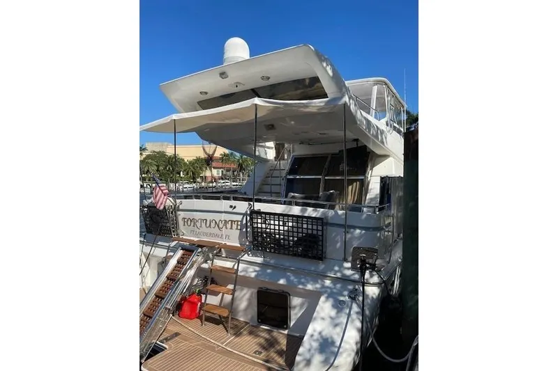 Slide: The Image of 1995 Johnson Flybridge Motoryacht docked, featuring spacious deck and canopy, sunny day. - 8