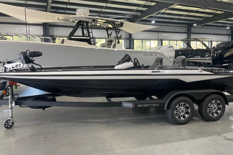 Slide: The Image of 2026 Skeeter ZXR20 SE boat in showroom, black and white design, on trailer. - 2