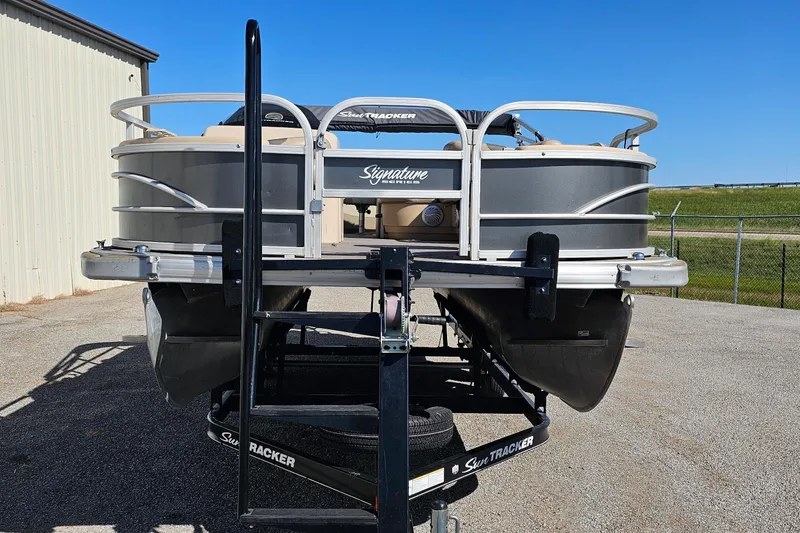 Slide: The Image of 2016 Sun Tracker Fishin' Barge 22 DLX pontoon boat on trailer, parked outdoors. - 2