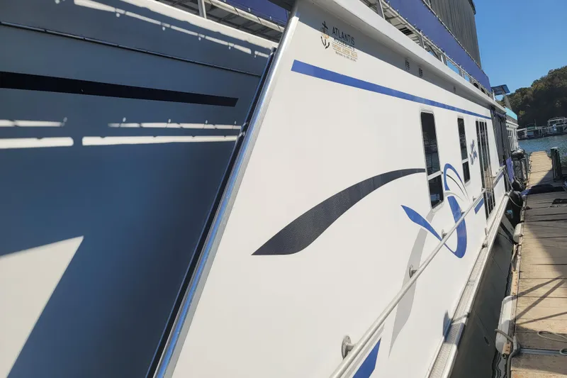 Slide: The Image of 2002 Fantasy 16 X 68 Houseboat docked, featuring sleek design and blue accents. - 3