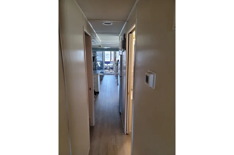 Slide: The Image of Narrow hallway inside a 2002 Fantasy 16 X 68 houseboat, leading to a bright living area. - 34