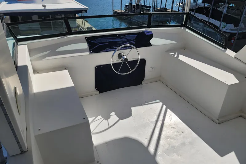 Slide: The Image of 2002 Fantasy 16 X 68 Houseboat helm with steering wheel and seating, docked by the water. - 5