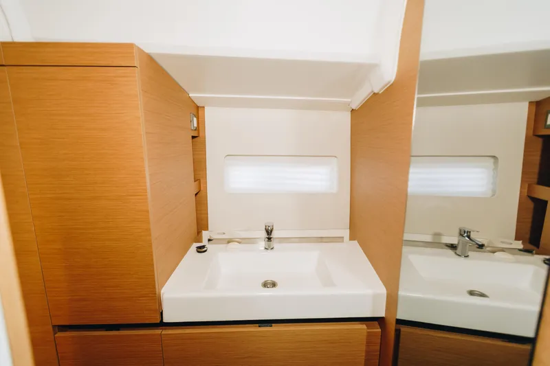 Slide: The Image of Modern bathroom interior of 2023 Jeanneau Sun Odyssey 490 yacht, featuring sleek sink and wood cabinetry. - 29
