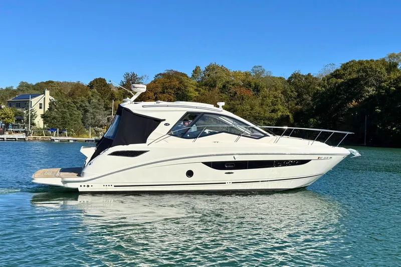 Slide: The Image of 2017 Sea Ray Sundancer 350 Coupe cruising on a serene lake with lush greenery. - 0