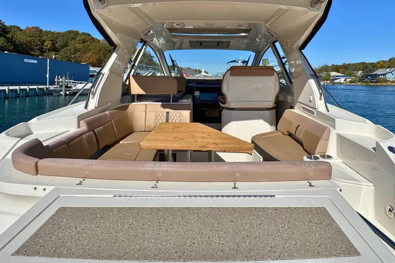 Slide: The Image of 2017 Sea Ray Sundancer 350 Coupe interior with seating and table, docked by the water. - 11