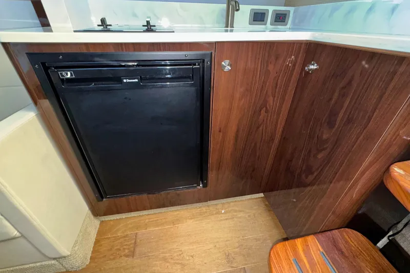 Slide: The Image of 2017 Sea Ray Sundancer 350 Coupe interior with wood cabinetry and compact fridge. - 19