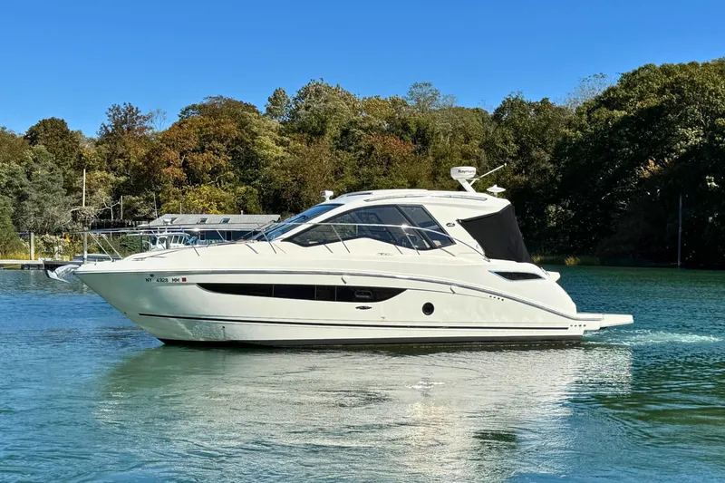 Slide: The Image of 2017 Sea Ray Sundancer 350 Coupe cruising on a serene lake with lush trees. - 2