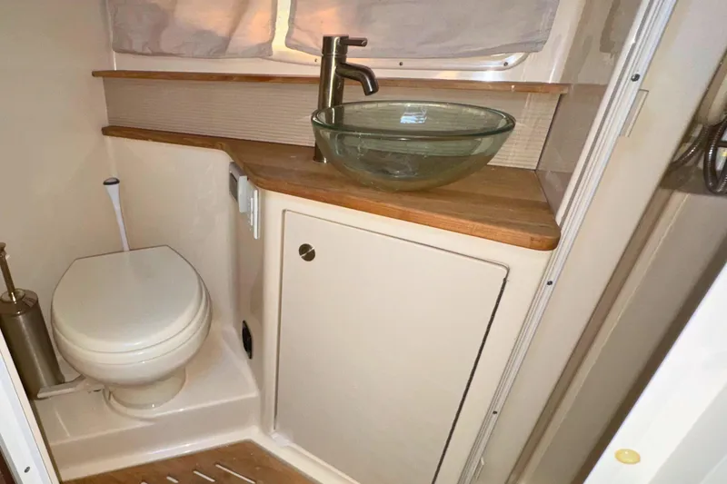 Slide: The Image of 2017 Sea Ray Sundancer 350 Coupe bathroom with glass sink and wooden countertop. - 23