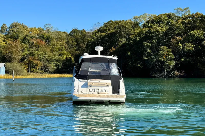 Slide: The Image of 2017 Sea Ray Sundancer 350 Coupe cruising on a serene lake with lush green trees. - 7