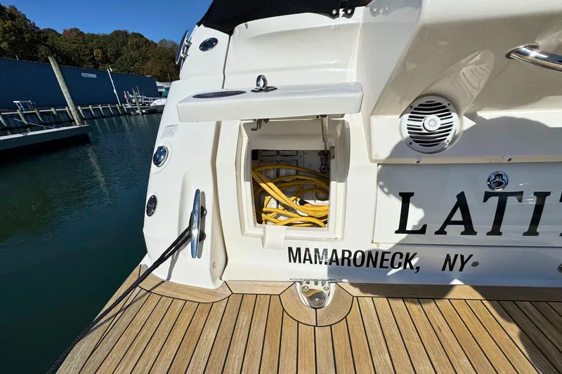 Slide: The Image of 2017 Sea Ray Sundancer 350 Coupe docked, showing storage compartment and marina background. - 9