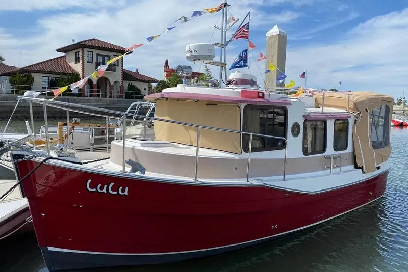 The Image of 2009 Ranger Tugs R-25 boat docked, adorned with colorful flags and beige canopy. - 0