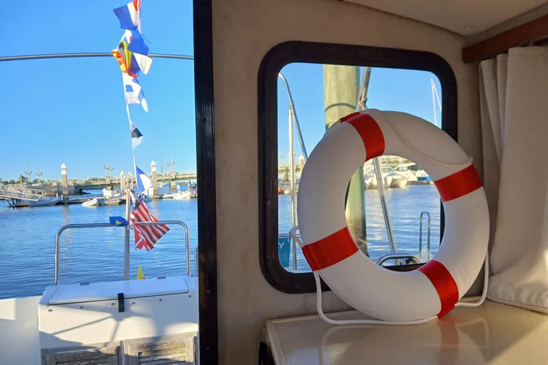 Slide: The Image of 2009 Ranger Tugs R-25 interior with life ring, docked at marina, nautical flags displayed. - 13