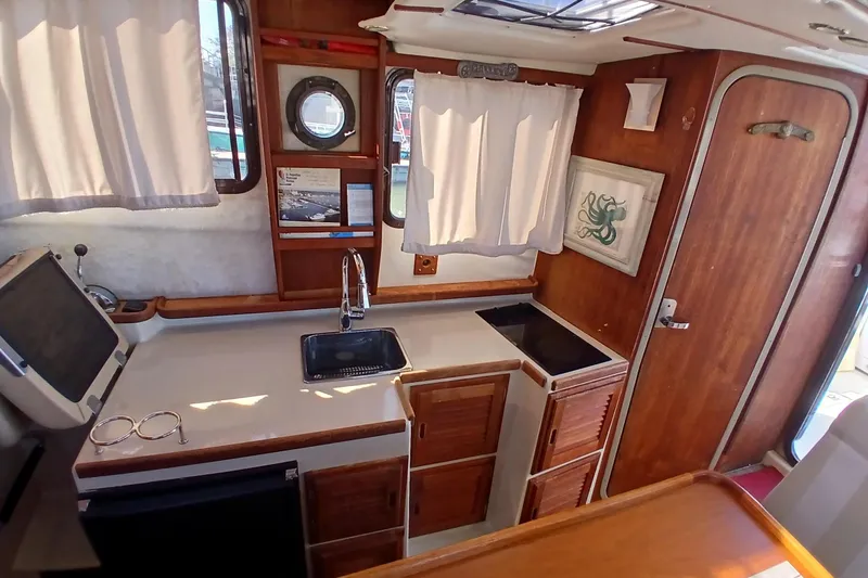 Slide: The Image of 2009 Ranger Tugs R-25 interior with kitchenette, sink, and wooden cabinetry. - 17