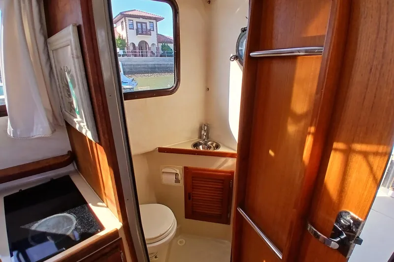 Slide: The Image of 2009 Ranger Tugs R-25 boat interior with compact bathroom and wooden cabinetry. - 19
