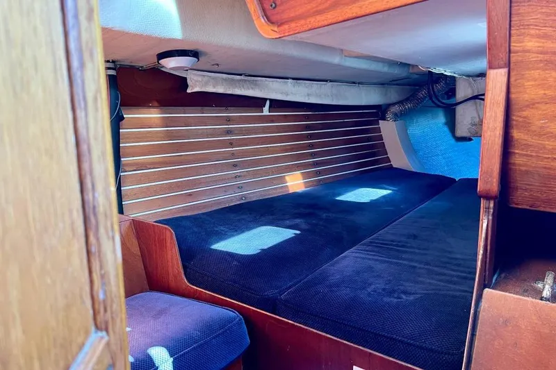 Slide: The Image of Interior cabin of a 1982 Santa Cruz 50 sailboat with wooden paneling and blue cushions. - 15