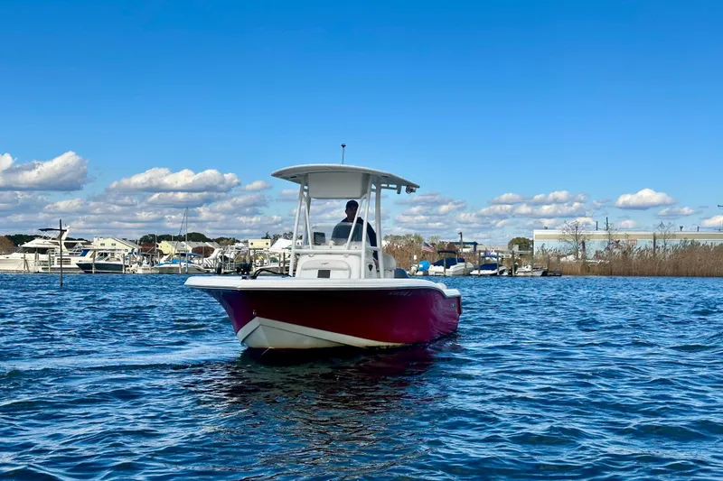 Slide: The Image of 2013 Tidewater 210 LXF boat cruising on a sunny day with marina in background. - 3