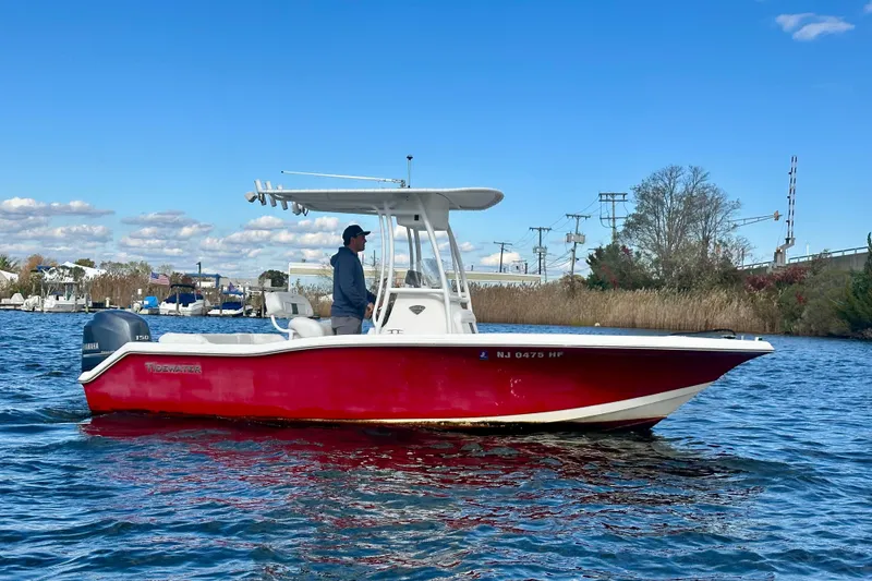 Slide: The Image of 2013 Tidewater 210 LXF boat with red hull on a sunny day, cruising on water. - 5