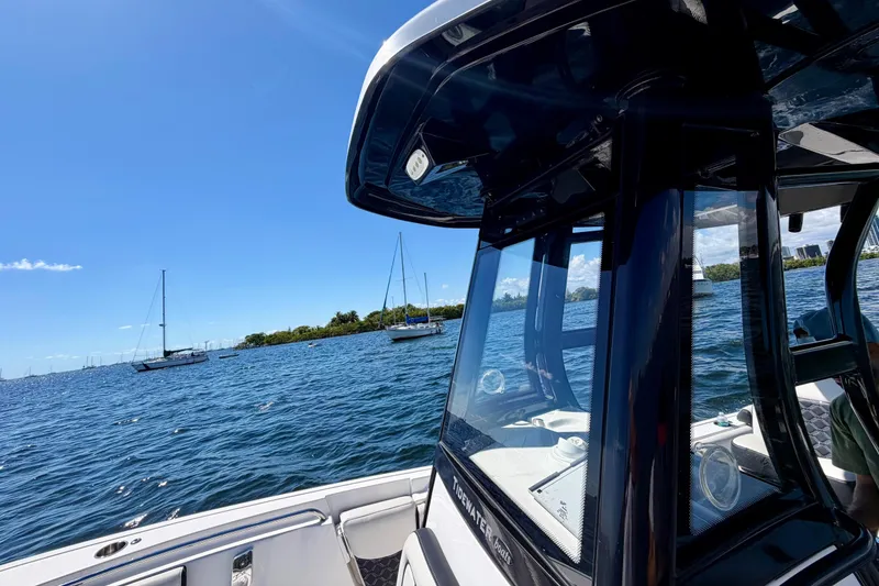 Slide: The Image of 2023 Tidewater 232 LXF boat on a sunny day, with sailboats in the background. - 11