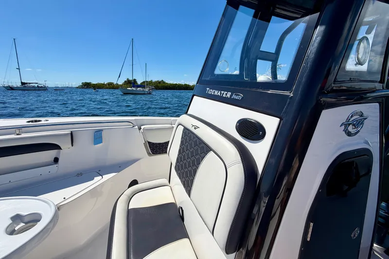 Slide: The Image of 2023 Tidewater 232 LXF boat interior with seating, on a sunny day by the water. - 12