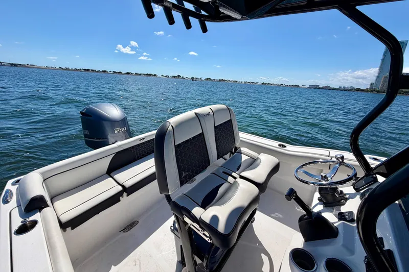 Slide: The Image of 2023 Tidewater 232 LXF boat interior with seating and steering, overlooking calm blue waters. - 19