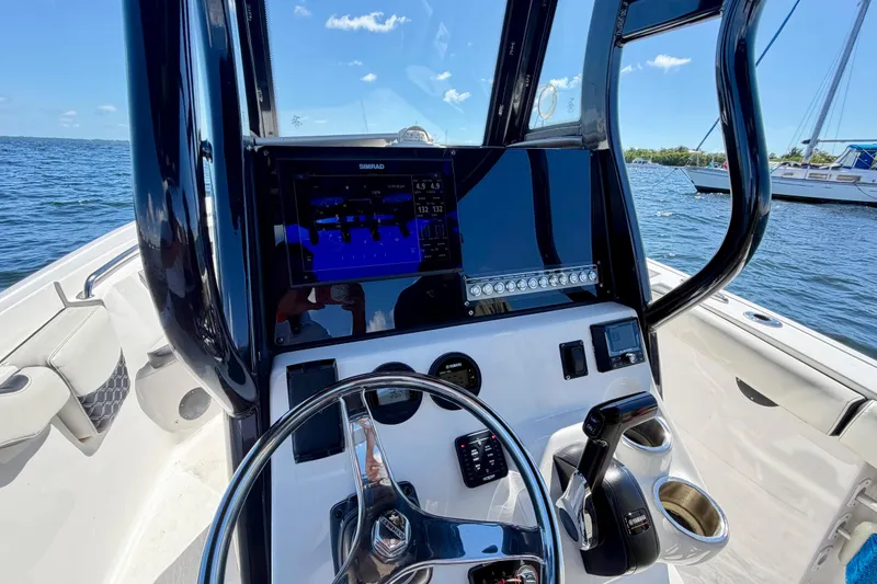 Slide: The Image of 2023 Tidewater 232 LXF boat dashboard with navigation controls and display on open water. - 6