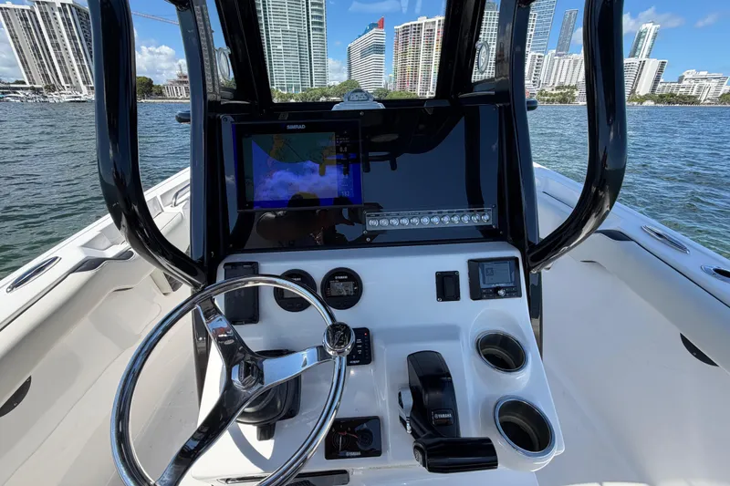 Slide: The Image of 2023 Tidewater 232 LXF boat dashboard with steering wheel and navigation system, city skyline in background. - 7