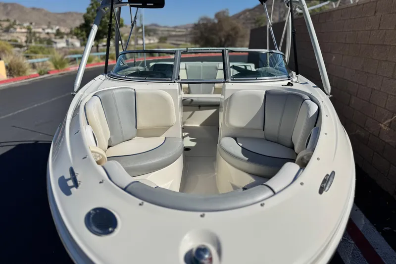 Slide: The Image of 2006 Bayliner 215 Bowrider boat with spacious seating, parked outdoors. - 11
