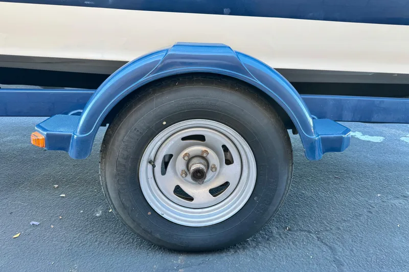 Slide: The Image of Trailer wheel of a 2006 Bayliner 215 Bowrider boat, blue fender visible. - 25