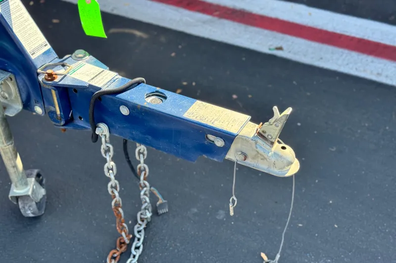 Slide: The Image of Trailer hitch of a 2006 Bayliner 215 Bowrider on asphalt, with safety chains attached. - 26