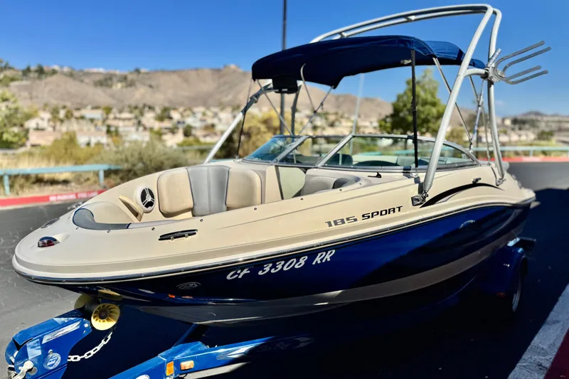 Slide: The Image of 2006 Bayliner 215 Bowrider boat with blue hull and canopy on trailer. - 3