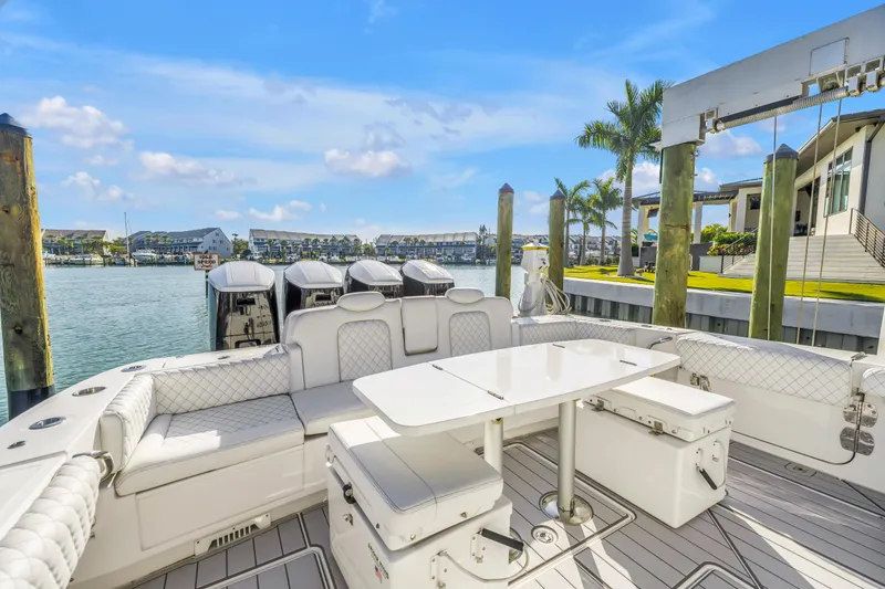 Slide: The Image of 2023 HCB 53 Suenos RXV luxury boat interior with seating and table, docked by waterfront homes. - 110