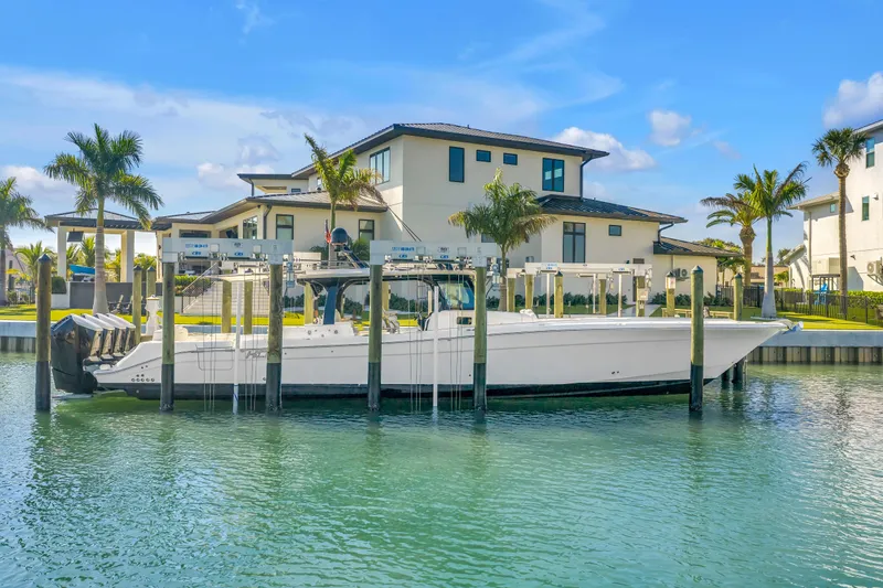 Slide: The Image of 2023 HCB 53 Suenos RXV boat docked near luxury waterfront homes. - 14