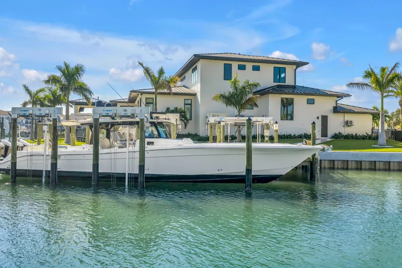Slide: The Image of 2023 HCB 53 Suenos RXV boat docked by a modern waterfront home. - 16