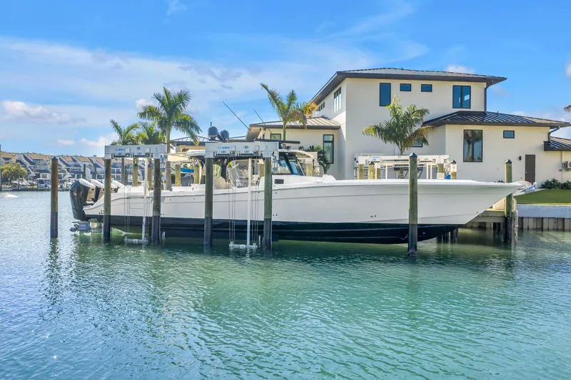 Slide: The Image of 2023 HCB 53 Suenos RXV boat docked by waterfront home with palm trees. - 18