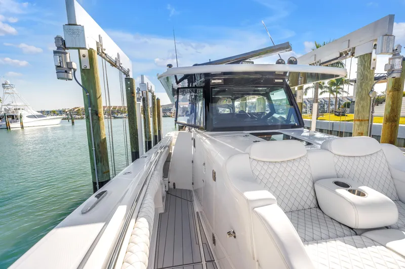 Slide: The Image of 2023 HCB 53 Suenos RXV luxury boat docked at marina, featuring plush seating. - 34