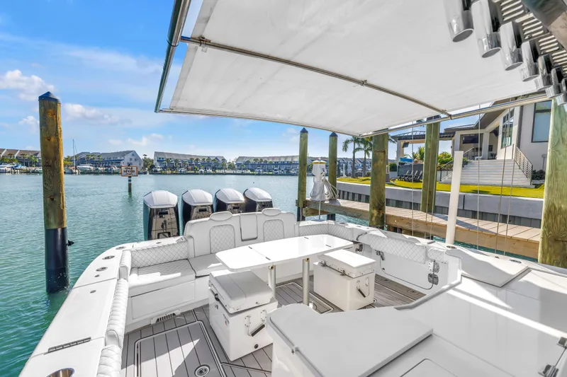 Slide: The Image of 2023 HCB 53 Suenos RXV luxury boat docked, featuring spacious seating and multiple outboard engines. - 49