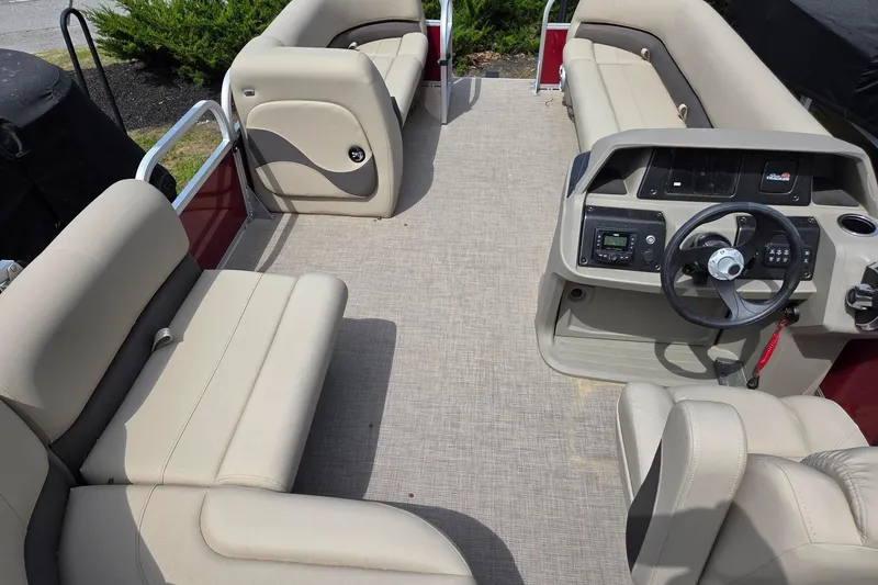 Slide: The Image of 2026 Sun Tracker Party Barge 18 DLX interior with beige seating and steering console. - 9