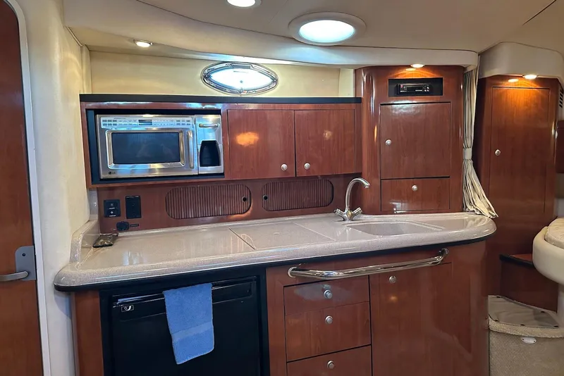 Slide: The Image of 2006 Sea Ray 340 Sundancer galley with wood cabinetry, microwave, and sink. - 13